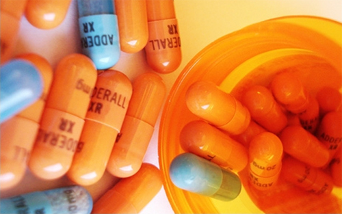 photo of blue and orange adderall capsules and a prescription bottle - is my child using adderall - freedom interventions